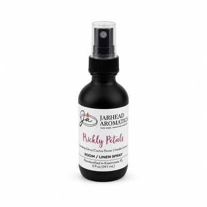 A black spray bottle labeled Jarhead Aromatics Prickly Petals Room & Linen Spray, featuring a desert-inspired fragrance with notes of cactus flower, coconut, and sandalwood. Bottle size is 2 fl oz (59 ml).