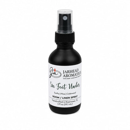 A 2 oz black spray bottle of Jarhead Aromatics Six Feet Under Room & Linen Spray, handcrafted in Kissimmee, FL and featuring captivating scents of damp earth, moss, and ancient oak for an inviting home fragrance.