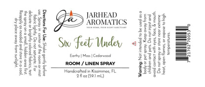 Rectangular label for Jarhead Aromatics’ Six Feet Under Room & Linen Spray | Damp Earth, Moss & Ancient Oak, highlighting its earthy fragrance of moss and ancient oak for an inviting home atmosphere. Label displays directions, warnings, barcode, logo, net weight of 2 fl oz (59.1 mL), and Kissimmee, FL location details.