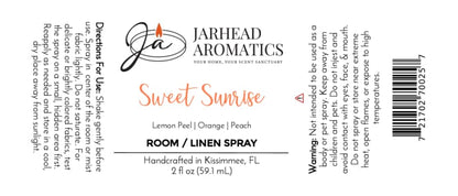 A label for Jarhead Aromatics Sweet Sunrise Room & Linen Spray | Lemon, Orange, Peach & Citrus, showcasing a lively citrus home fragrance blend with notes of lemon peel, orange, and peach. The white background features black and orange text detailing instructions, warnings, and product information—perfectly accentuating this inviting fruity spray from Jarhead Aromatics.
