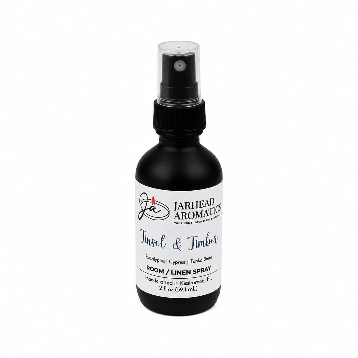 A small black spray bottle with a white label reading Tinsel & Timber Room & Linen Spray | Eucalyptus, Pine, Smoke & Tonka, a winter forest scent.