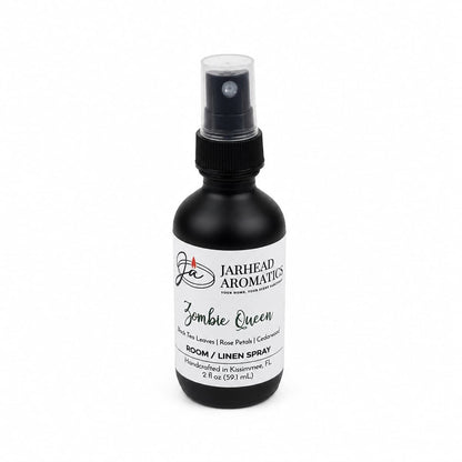 A black spray bottle labeled Zombie Queen Room & Linen Spray by Jarhead Aromatics, featuring notes of black tea, rose petals, and cedarwood. This elegant gothic home fragrance comes in a 2 fl oz bottle with a dark floral scent, complete with a white label and black text—perfect for adding an air of mystery to any room or linen.