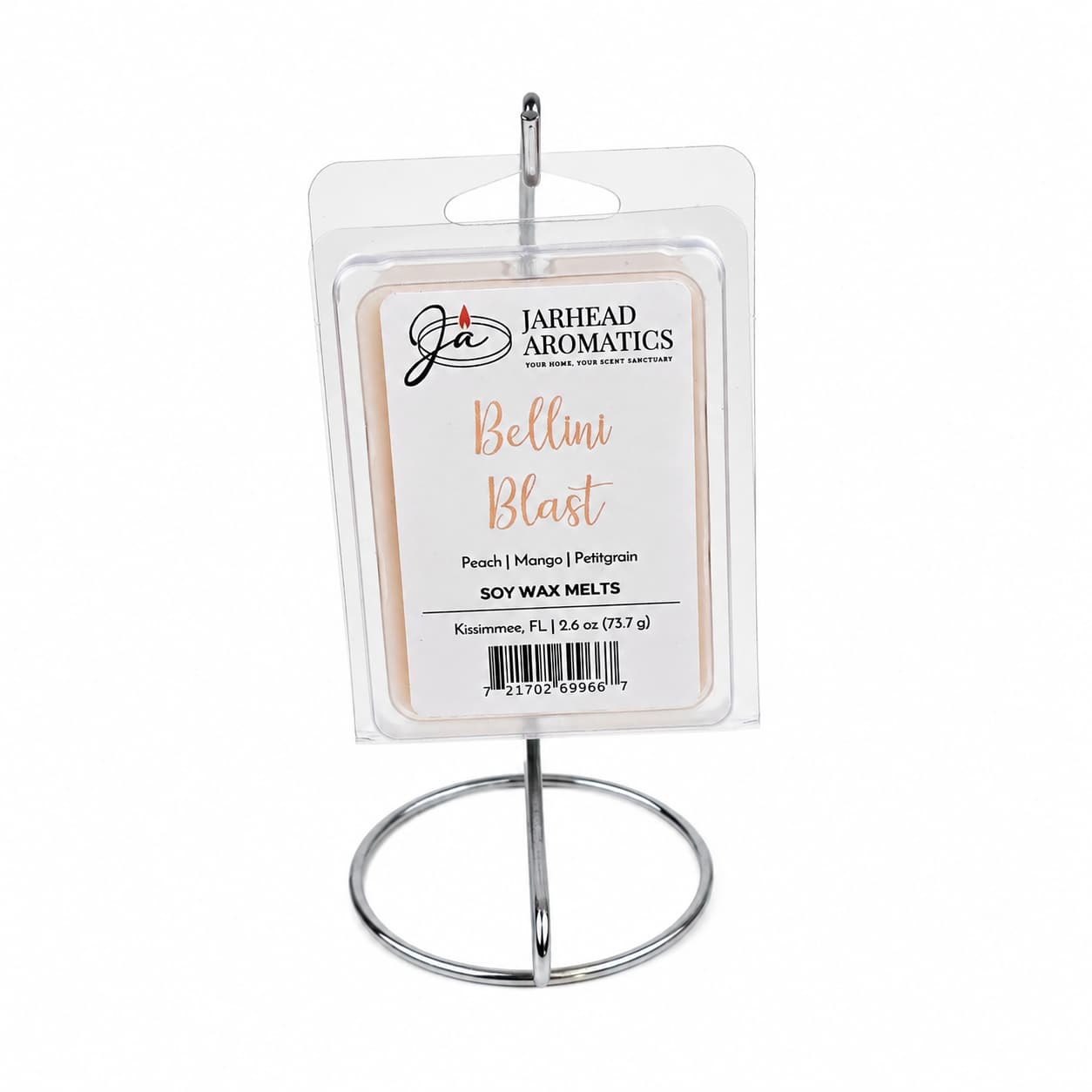 A package of Jarhead Aromatics Bellini Blast Soy Wax Melt | Tangerine, Peach & Tropical Mango sits on a silver metal display stand. The label highlights scent notes of tangerine, peach, and tropical mango, with a product weight of 6.2 oz (175 g), offering a vibrant tropical fragrance in every soy wax melt.