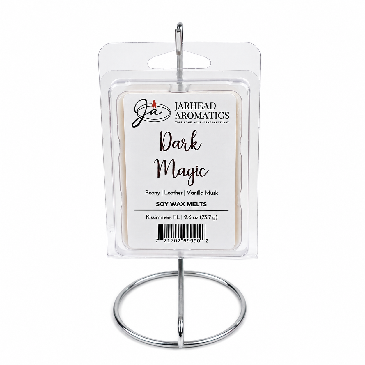 A package of Jarhead Aromatics Dark Magic Soy Wax Melt rests elegantly on a silver metal stand. The label showcases its premium fragrance notes—peach, plum, dark florals, and vanilla musk—and features a barcode, emphasizing these soy wax melts crafted with care.