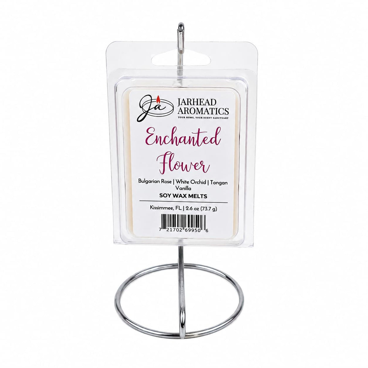 A package of Jarhead Aromatics Enchanted Flower Soy Wax Melt is displayed on a silver metal stand. This fragrance blends Bulgarian rose, white orchid, vanilla, and tangerine notes.