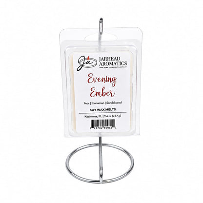 A package of Jarhead Aromatics Evening Ember Soy Wax Melt is displayed upright on a metal stand. The label highlights its captivating blend of plum, sandalwood, and soft smoke. This premium soy wax melt by Jarhead Aromatics infuses any space with a warm, inviting ambiance.