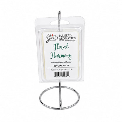 A package of Jarhead Aromatics Floral Harmony Soy Wax Melt | Gardenia, Jasmine & Tuberose is displayed upright on a silver metal stand. The label highlights the blend of gardenia, jasmine, and tuberose fragrances, offering a long-lasting and elegantly floral scent.