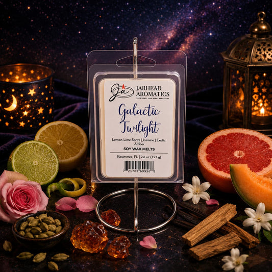A package of Jarhead Aromatics’ Galactic Twilight Soy Wax Melt | Bergamot, Amber & Sandalwood is displayed with candles on a velvet cloth, surrounded by elements like limes, grapefruit, rose, incense, and cardamom, all set against a starry galaxy background.