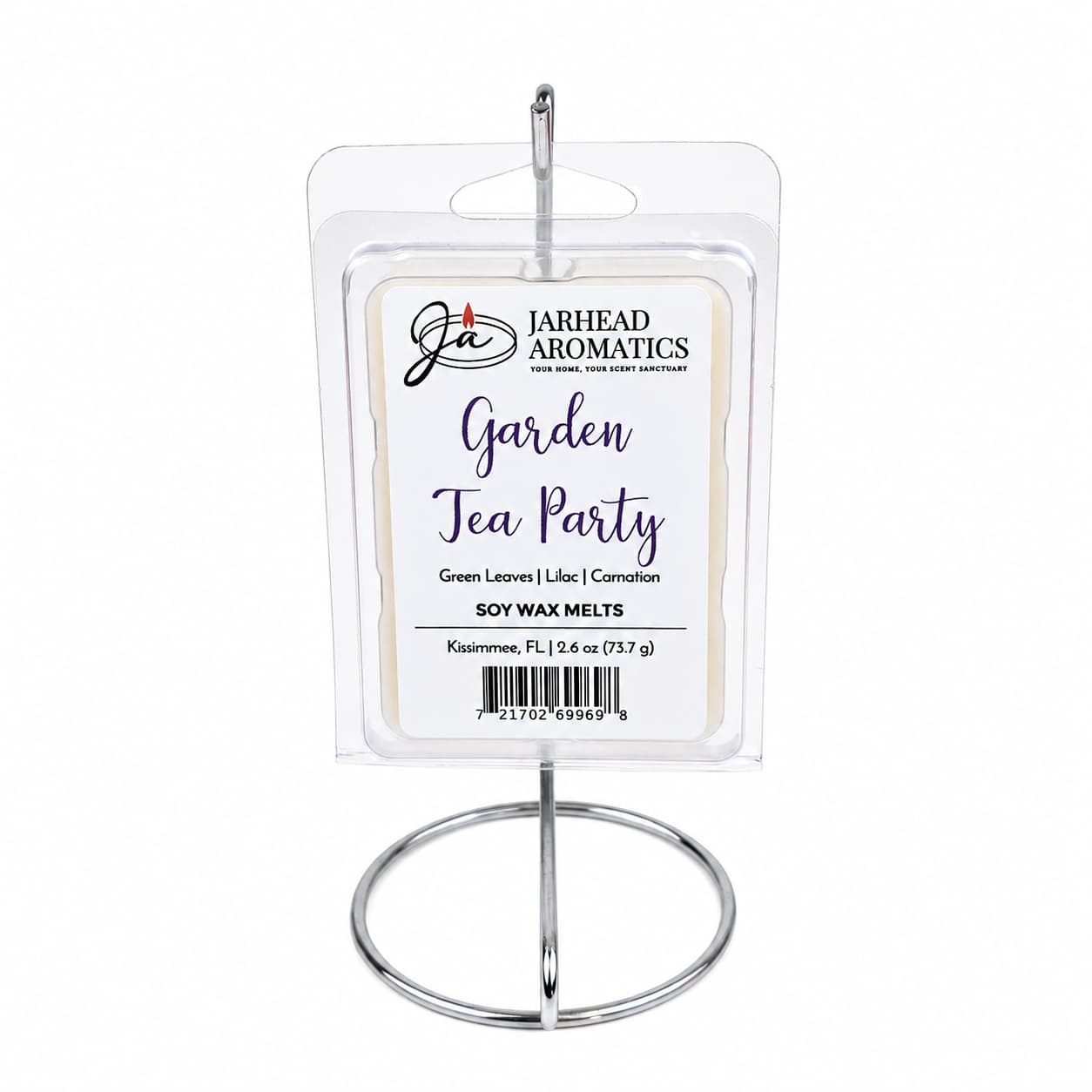 A package of Jarhead Aromatics Garden Tea Party Soy Wax Melt | Rose, Lilac & Jasmine sits elegantly on a silver metal stand. Infused with a charming floral fragrance, the label highlights notes of rose, lilac, and jasmine, perfectly capturing the essence of a tranquil garden tea party.