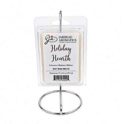 A package of Holiday Hearth Soy Wax Melt | Cinnamon Clove & Bayberry Holiday Scent by Jarhead Aromatics in a clear plastic clamshell, hanging from a circular wire display stand.