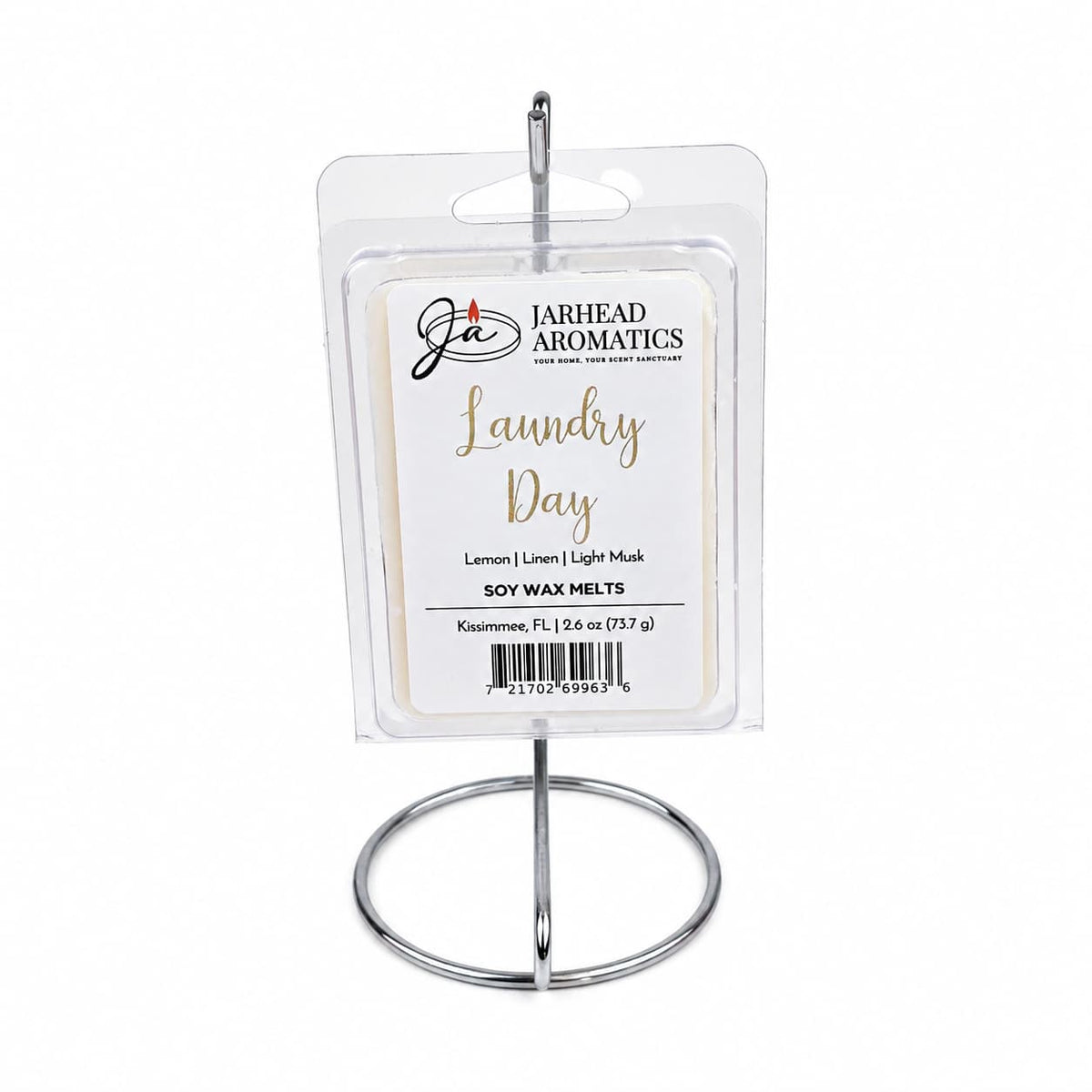 A package of Jarhead Aromatics’ Laundry Day Soy Wax Melt | Fresh Linen, Lemon & Clean Musk rests gracefully on a metal stand. The transparent packaging highlights a sophisticated white and gold label featuring the scent notes: Fresh Linen, Lemon, and Clean Musk. Ideal for anyone who loves home fragrance, these soy wax melts envelop your space in the revitalizing aroma of freshly laundered linens mixed with bright lemon and clean musk—bringing the crisp essence of laundry day into any room.
