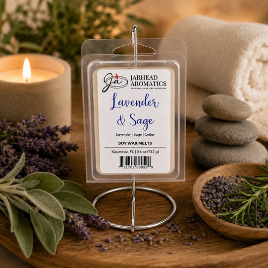 A pack of Jarhead Aromatics Lavender & Sage Soy Wax Melt | Lavender, Sage & Sandalwood is displayed alongside lavender sprigs, smooth stones, a lit candle, and a rolled towel, evoking a soothing spa-like atmosphere. This herbal soy wax melt blend fills your home with the calming aroma of lavender, sage, and sandalwood for true tranquility.