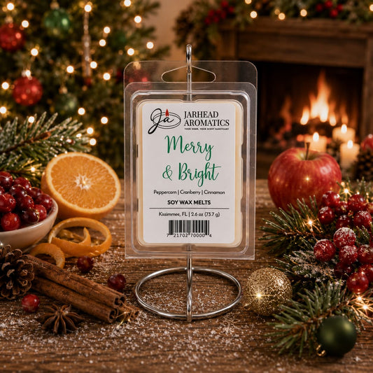 A Jarhead Aromatics Merry & Bright Soy Wax Melt plastic clamshell package sits on a wooden table surrounded by oranges, cranberries, cinnamon sticks, pine branches, and ornaments in front of a fireplace.