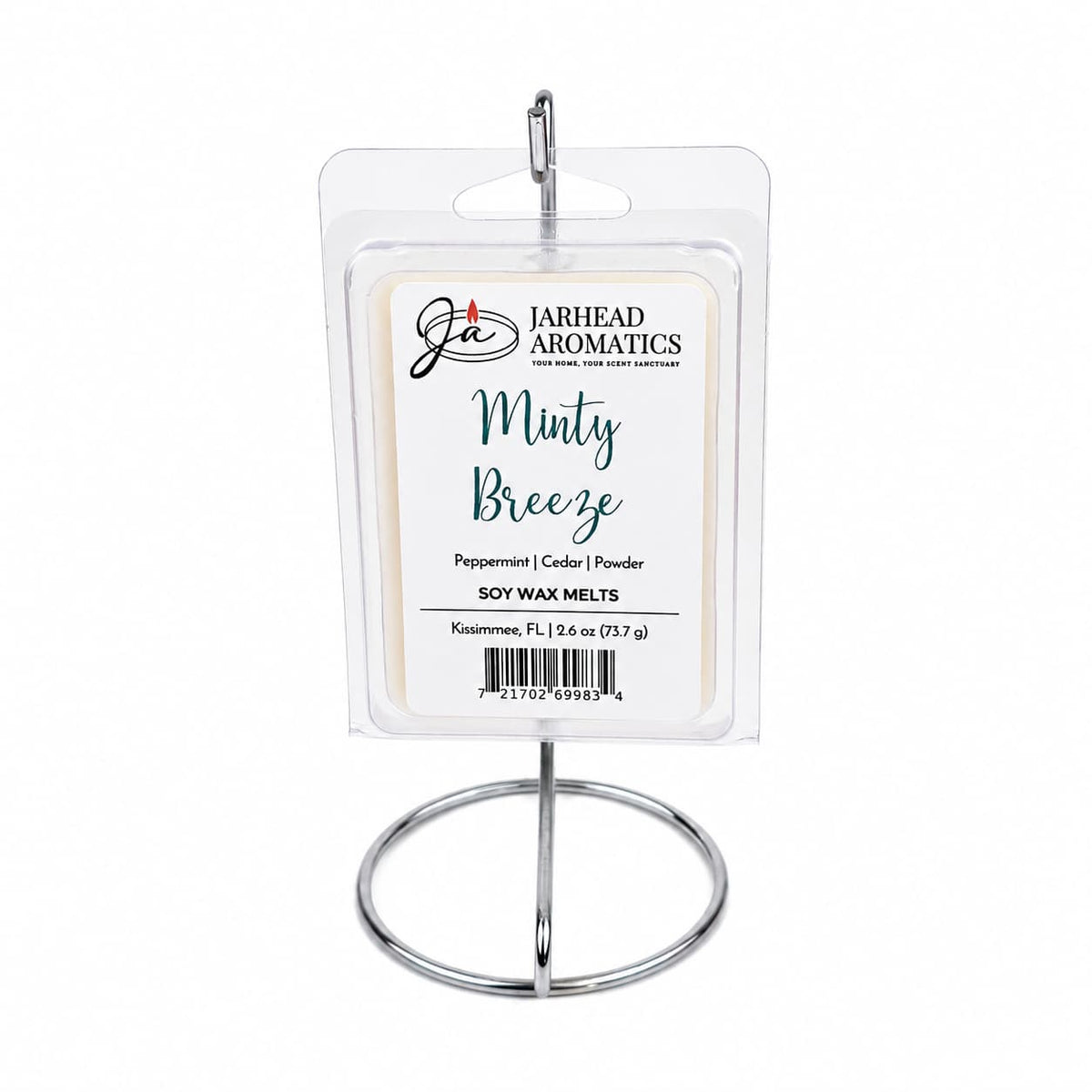 A package of Jarhead Aromatics Minty Breeze Soy Wax Melt | Peppermint, Eucalyptus & Cedarwood is displayed on a metal stand. The label highlights peppermint, eucalyptus, and cedarwood scents, as well as the wax weight and origin. Infused with a refreshing peppermint eucalyptus fragrance, this soy wax melt from Jarhead Aromatics creates a relaxing atmosphere that’s perfect for any space.