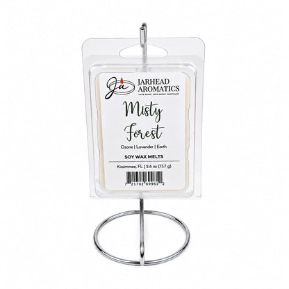A package of Jarhead Aromatics Misty Forest Soy Wax Melt | Moss, Juniper & Rain-Kissed Woods is displayed upright on a silver metal stand against a white background, perfect for bringing a natural home fragrance into your space.