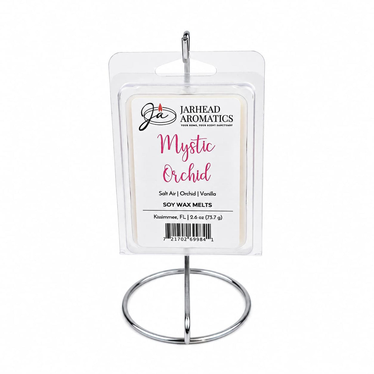 A package of Jarhead Aromatics Mystic Orchid Soy Wax Melt | Orchid, Salt Air & Vanilla is displayed on a metal stand. The label highlights scents of orchid, salt air, and vanilla for a true coastal home fragrance experience. The packaging features white and pink text and showcases the premium soy wax inside through its clear wrapping.