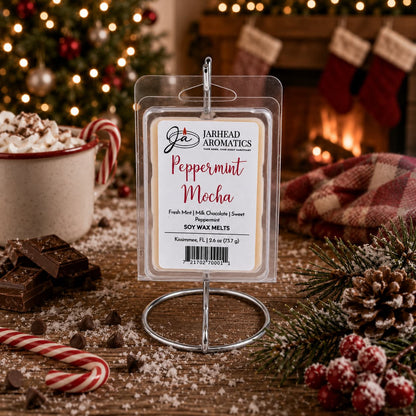 A Peppermint Mocha Soy Wax Melt in a clear plastic clamshell package, displayed on a metal stand on a wooden table with holiday decorations.
