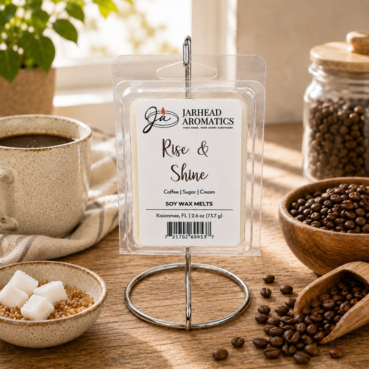A package of Jarhead Aromatics Rise & Shine Soy Wax Melt | Fresh Coffee, Sugar & Cream rests on a metal holder, surrounded by a coffee cup, a bowl of coffee beans, sugar cubes, and a jar of beans on a sunlit table, filling the air with the inviting aroma of fresh coffee blended with sugar and cream.