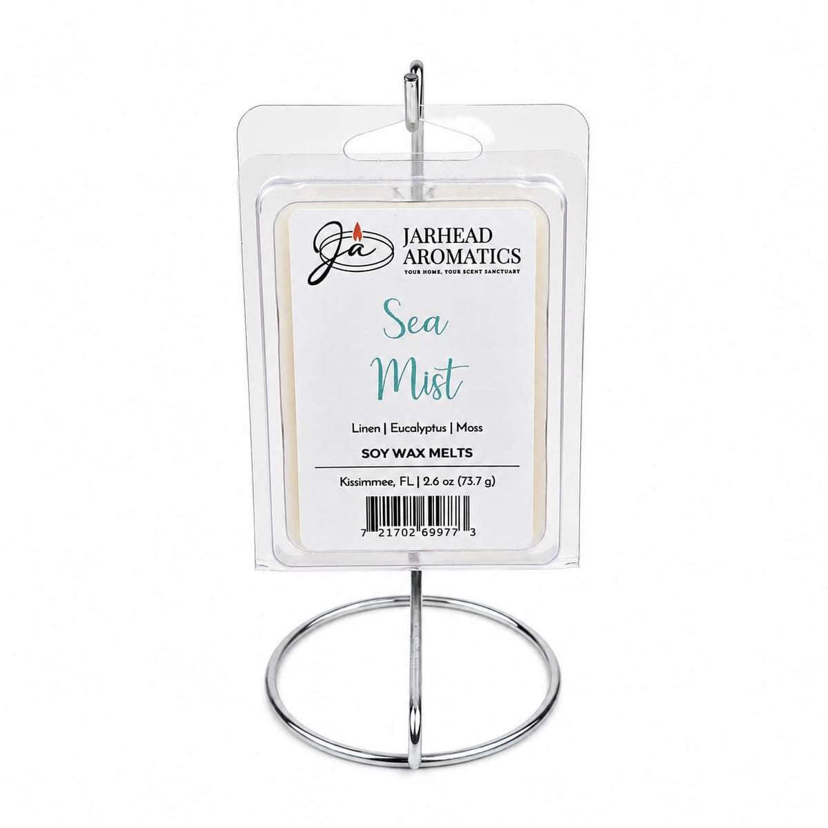 A package of Jarhead Aromatics Sea Mist Soy Wax Melt | Fresh Linen, Sea Salt & Eucalyptus is displayed upright on a silver metal stand. The label highlights notes of fresh linen, sea salt, and eucalyptus, evoking a spa-inspired aroma and bringing a refreshing coastal fragrance to your space.
