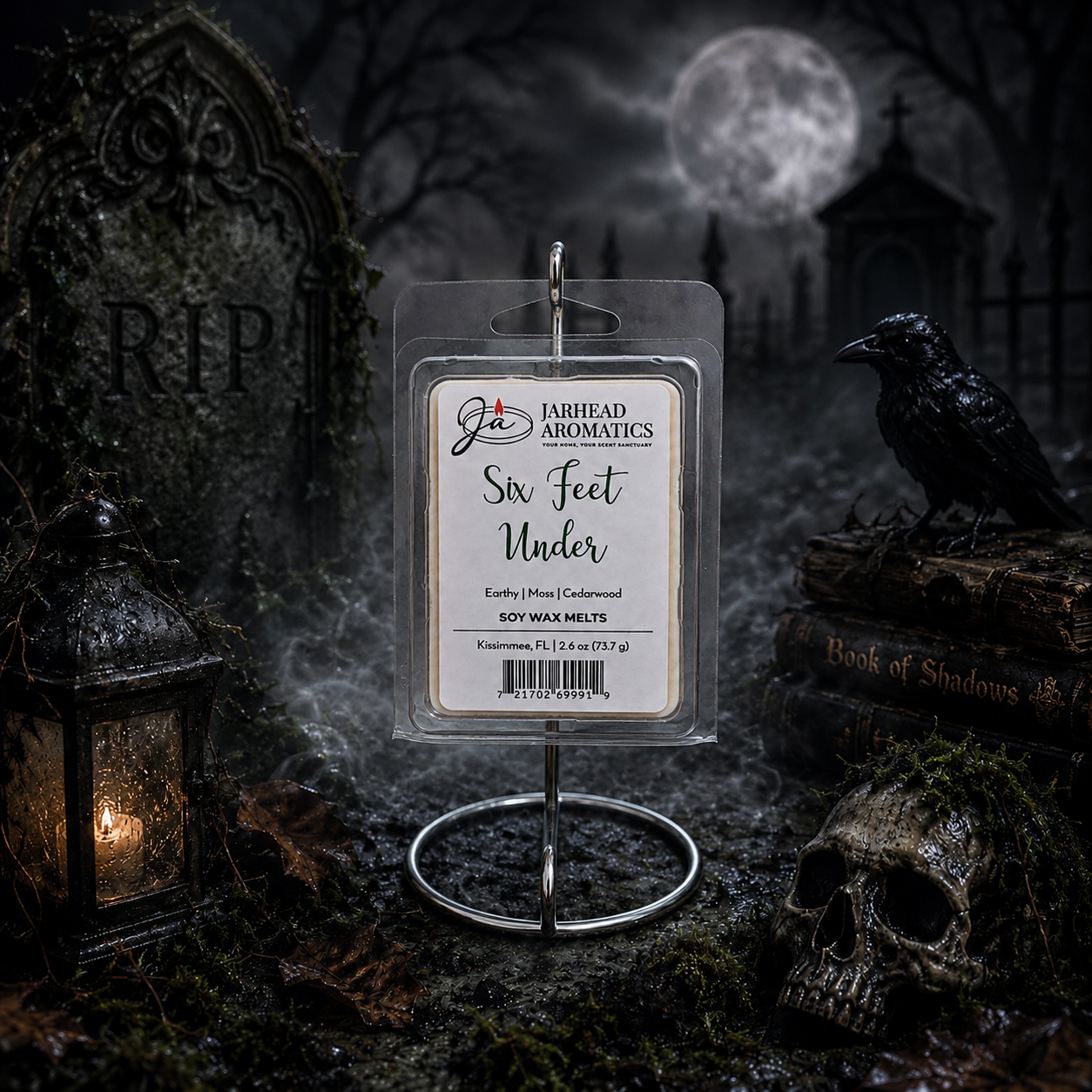 A package of Six Feet Under Soy Wax Melt | Damp Earth, Moss & Ancient Oak from Jarhead Aromatics is displayed in a spooky graveyard scene complete with a lantern, skull, raven, tombstones, and a full moon in the background. The dark atmospheric fragrance of damp earth, moss, and ancient oak perfectly enhances the eerie ambiance of this chilling tableau.