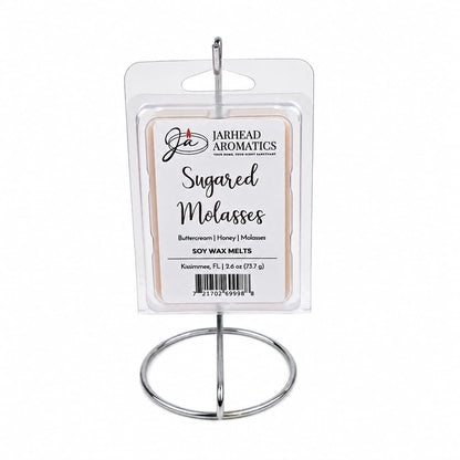 A package of Jarhead Aromatics Sugared Molasses Soy Wax Melt | Buttercream, Honey & Dark Molasses is displayed on a metal stand. These hand-poured soy wax melts feature comforting notes of buttercream, honey, and dark molasses to fill your space with a highly fragrant sweetness.