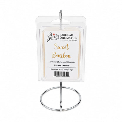 A pack of Jarhead Aromatics Sweet Bourbon Soy Wax Melt is showcased on a silver stand. The clear plastic packaging features a beige and white label that highlights the inviting notes of bourbon, butterscotch, and brown sugar, creating a warm gourmand fragrance for your space and promising long-lasting scent.