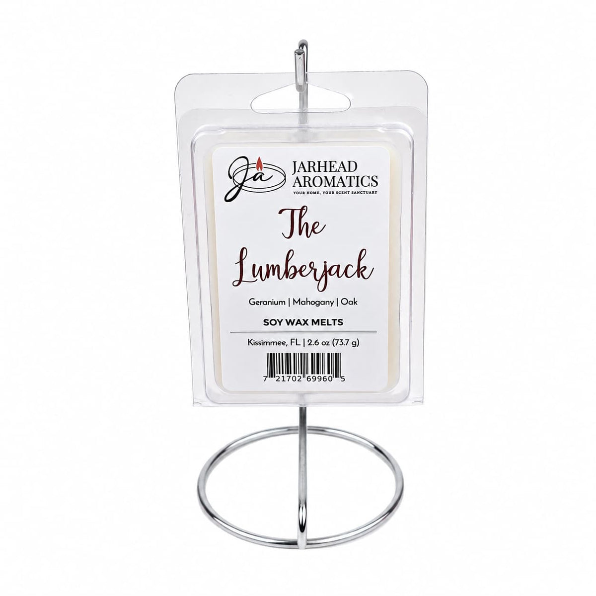A clamshell package labeled The Lumberjack Soy Wax Melt by Jarhead Aromatics is displayed on a metal stand. Infused with a rich woodsy fragrance, the scent notes listed are mahogany, cedarwood, and oak.