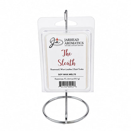 A package of Jarhead Aromatics The Sleuth Soy Wax Melt, featuring notes of leather, rosewood, and sandalwood, is displayed on a metal stand.