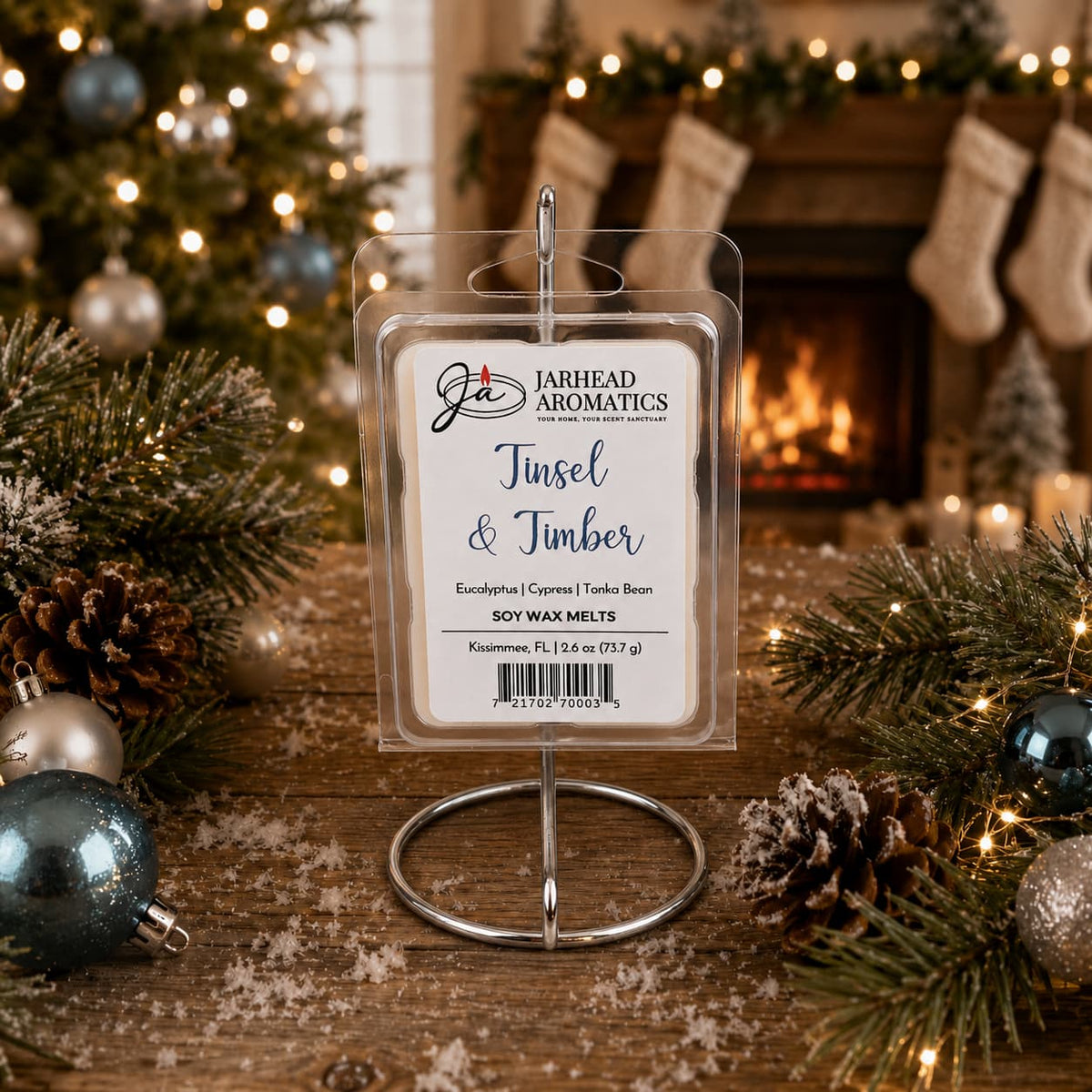A package of Tinsel & Timber Soy Wax Melt | Fresh Pine Christmas Tree Holiday Scent in a circular wire stand sits on a wooden surface decorated with pine branches, pinecones, and Christmas ornaments in front of a fireplace.