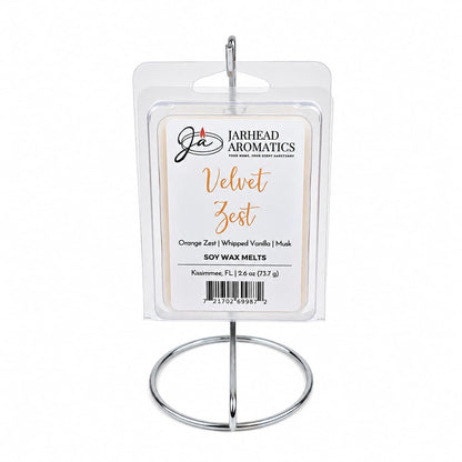 A package of Jarhead Aromatics Velvet Zest Soy Wax Melt | Citrus, Vanilla & Caramel, celebrated for its irresistible gourmand fragrance, is displayed on a silver metal stand against a white background.