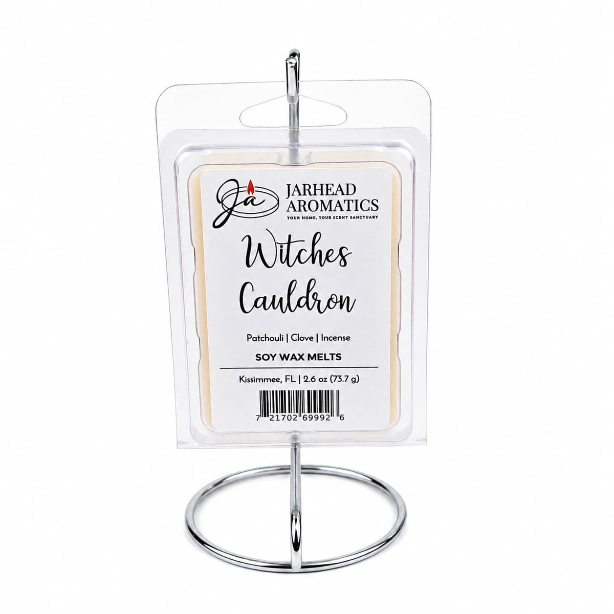 A package of Jarhead Aromatics Witches Cauldron Soy Wax Melt is displayed on a silver stand. The label highlights orange blossom, patchouli, and dark incense as the featured scents, promising a long-lasting fragrance in every soy wax melt.