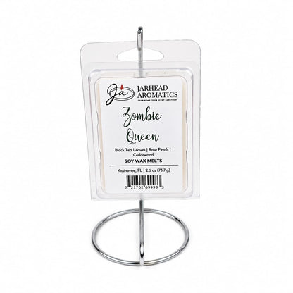 A package of Jarhead Aromatics Zombie Queen Soy Wax Melt—featuring the black tea, rose petals, and cedarwood fragrance—is displayed upright on a silver metal stand against a white background.
