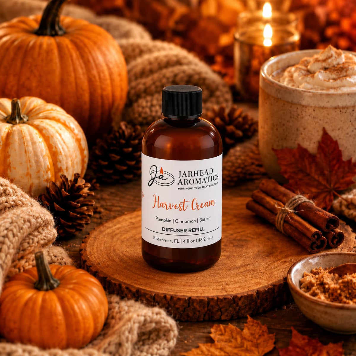 A bottle of Harvest Cream Diffuser Refill by Jarhead Aromatics, featuring notes of pumpkin spice, brown sugar, and vanilla cream, sits atop a wooden slab surrounded by pumpkins, pine cones, autumn leaves, cinnamon sticks, and a cozy mug—creating a warm and inviting autumn-themed scene that evokes the comforting aroma of an autumn home fragrance.