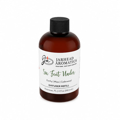 A brown bottle labeled Jarhead Aromatics Six Feet Under Diffuser Refill, showcasing the Damp Earth, Moss & Ancient Oak fragrance for a rich, earthy home scent. This 4 fl oz cedarwood diffuser refill is displayed on a white background.