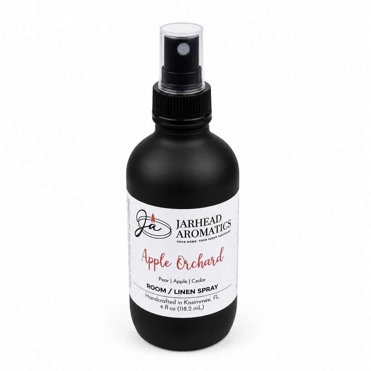 A black spray bottle labeled Jarhead Aromatics Apple Orchard Room & Linen Spray features a blend of crisp apple, pear, and cedarwood. This handcrafted 4 fl oz home fragrance was made in Kissimmee, FL.