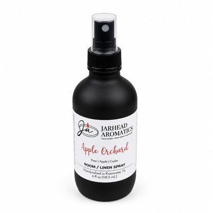 A black spray bottle labeled Jarhead Aromatics Apple Orchard Room & Linen Spray features a blend of crisp apple, pear, and cedarwood. This handcrafted 4 fl oz home fragrance was made in Kissimmee, FL.