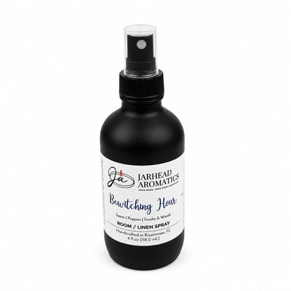 A black spray bottle labeled Jarhead Aromatics Bewitching Hour Room & Linen Spray, featuring exotic spices, dark florals, and smoky woods. Handcrafted in Kissimmee, FL, the bottle displays a white label with blue and black text for a home fragrance blend perfect for enchanting any space.