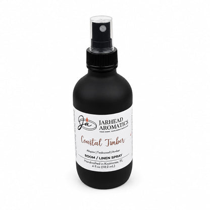 A black spray bottle of Jarhead Aromatics Coastal Timber Room & Linen Spray | Teakwood, Leather & Warm Amber, 4 fl oz, is displayed against a white background—this luxury home fragrance combines sophisticated woodsy notes of teakwood, leather, and warm amber to elevate any space.