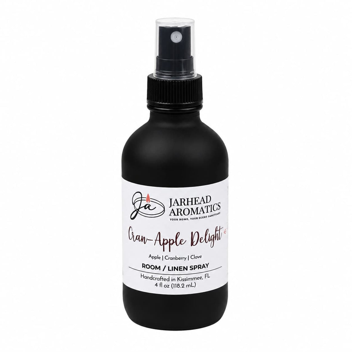 A black spray bottle labeled Jarhead Aromatics Cran-Apple Delight Room & Linen Spray offers a cozy blend of cranberry, apple, and warm cinnamon for an inviting home fragrance. This handcrafted 4 fl oz bottle is made in Kissimmee, FL.