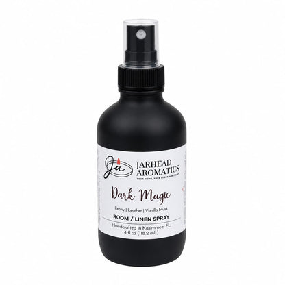 A black spray bottle labeled Jarhead Aromatics Dark Magic Room & Linen Spray with peach, plum, dark floral, and vanilla musk scents, 4 fl oz, handcrafted in Kissimmee, FL—an inviting home fragrance from Jarhead Aromatics.