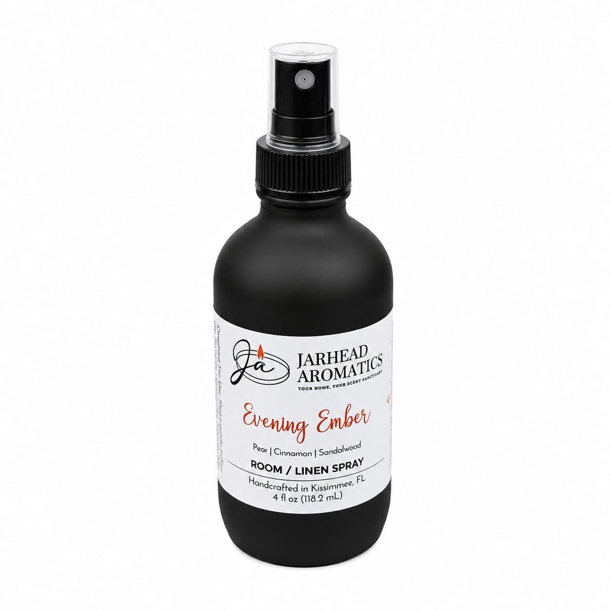 A black spray bottle labeled Jarhead Aromatics Evening Ember Room & Linen Spray, 4 fl oz, fills any space with a warm home fragrance featuring notes of plum, sandalwood, and soft smoke. The white-labeled bottle with a black cap is perfect for refreshing your room or linens.