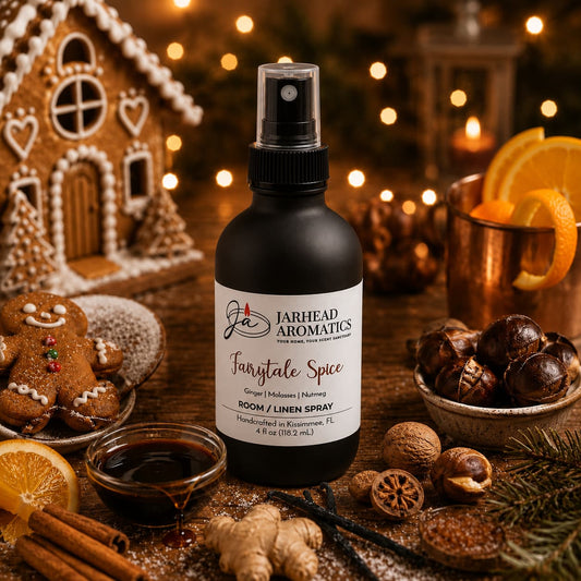 A bottle of Jarhead Aromatics Fairytale Spice Room & Linen Spray | Gingerbread, Molasses & Warm Spice is nestled among festive holiday accents—gingerbread cookies, orange slices, spices, copper mugs, and twinkling Christmas lights—evoking the warmth and coziness of a bakery-inspired home fragrance with comforting notes reminiscent of a gingerbread house.