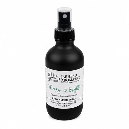 A black room and linen spray bottle with a white label featuring the Merry & Bright Room & Linen Spray | Citrus Cranberry, Warm Spice & Fir scent, notes of peppercorn, cranberry, and cinnamon, and text reading Room / Linen Spray.