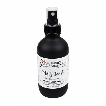 A 4 oz black spray bottle labeled “Jarhead Aromatics Misty Forest Room & Linen Spray,” handcrafted in Kissimmee, FL. The label highlights notes of ozone, moss, and juniper for a woodland scent that brings a nature-inspired home fragrance to any space.