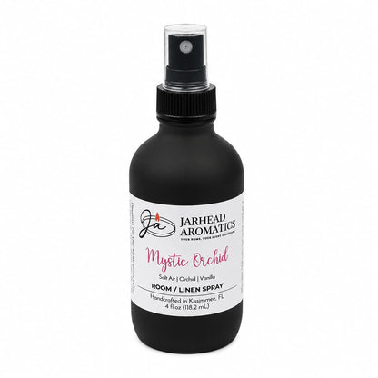 The Jarhead Aromatics Mystic Orchid Room & Linen Spray features a sleek black spray bottle and blends scent notes of orchid, salt air, and vanilla. Handcrafted in Kissimmee, FL, this home fragrance infuses your space with a refreshing coastal floral aroma, creating a serene oasis.