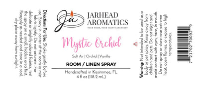 The Mystic Orchid Room & Linen Spray by Jarhead Aromatics features a label with directions, an ingredient list (orchid, salt air, and vanilla), warning information, a barcode, and a note stating it’s handcrafted in Kissimmee, FL. Designed with black and pink text on a white background, this label beautifully conveys the coastal floral essence of your favorite home fragrance.