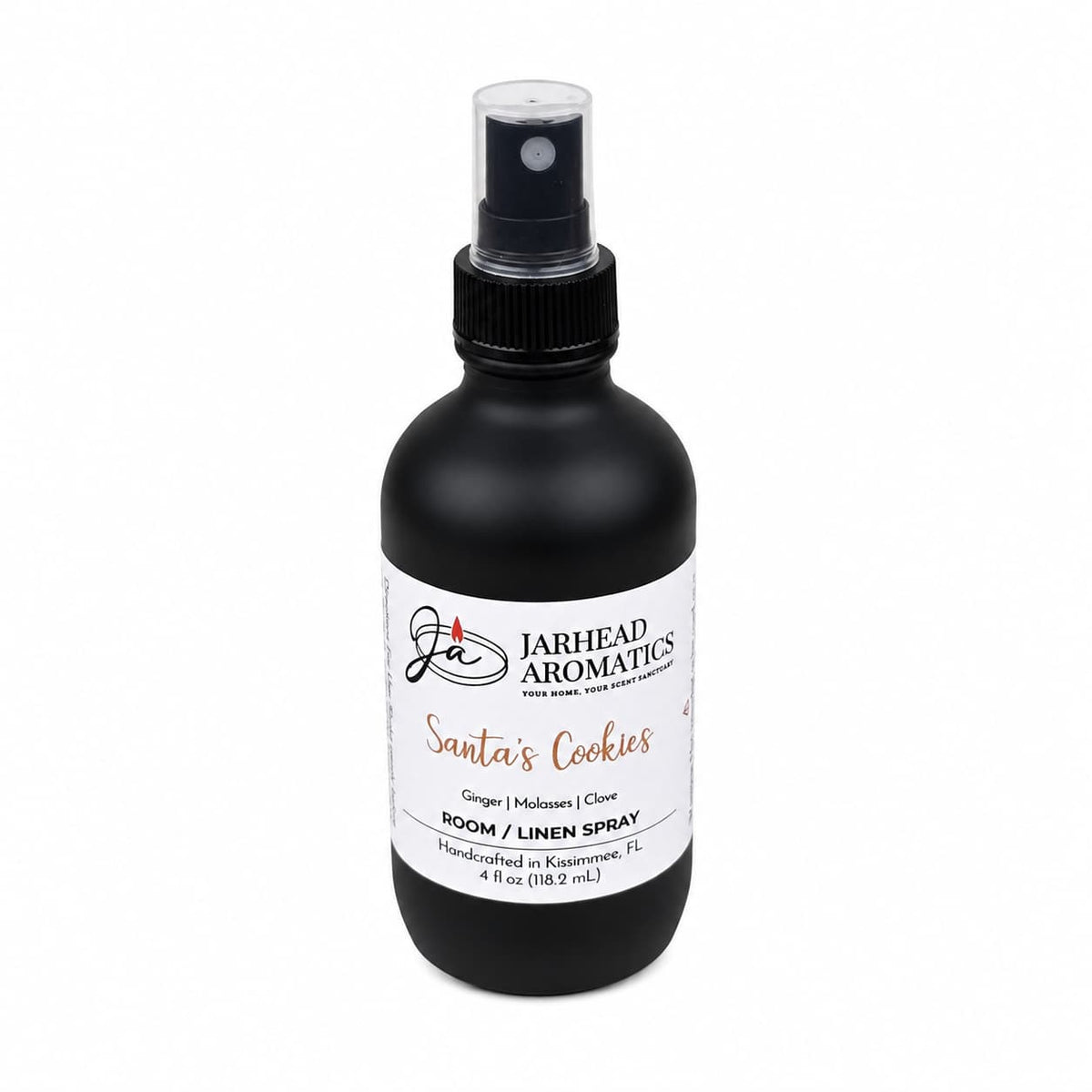 A black spray bottle with a white label reading Santa’s Cookies Room & Linen Spray, featuring scent notes of ginger, brown sugar, molasses, and vanilla to create a festive holiday fragrance.