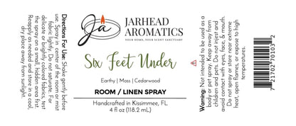 A white Jarhead Aromatics Six Feet Under Room & Linen Spray label showcases a candle logo, directions, scent notes (damp earth, moss & ancient oak), warning, barcode, and product information in black and green text—ideal for any home fragrance enthusiast.