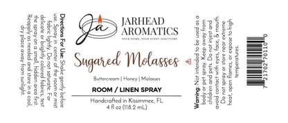 White product label for Jarhead Aromatics Sugared Molasses Room & Linen Spray | Buttercream, Honey & Dark Molasses, a gourmand home fragrance ideal for rooms or linens. Includes directions, warnings, and full ingredient list; features black, brown, and orange text with a flame logo.