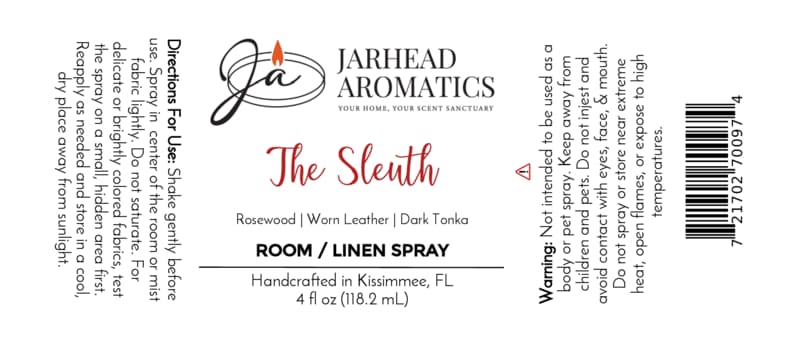 A Jarhead Aromatics The Sleuth Room & Linen Spray | Leather, Rosewood & Sandalwood label, displaying directions for use, safety warnings, the brand logo, and fragrance notes of rosewood, worn leather, dark tonka, and hints of sandalwood for a luxurious home aroma. Handcrafted in Kissimmee, FL. Net weight: 4 fl oz (118.2 ml).